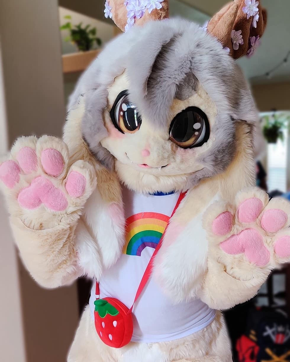 A fullsuit of a pastel yellow kemono jackalope with gray hair and pink accents.