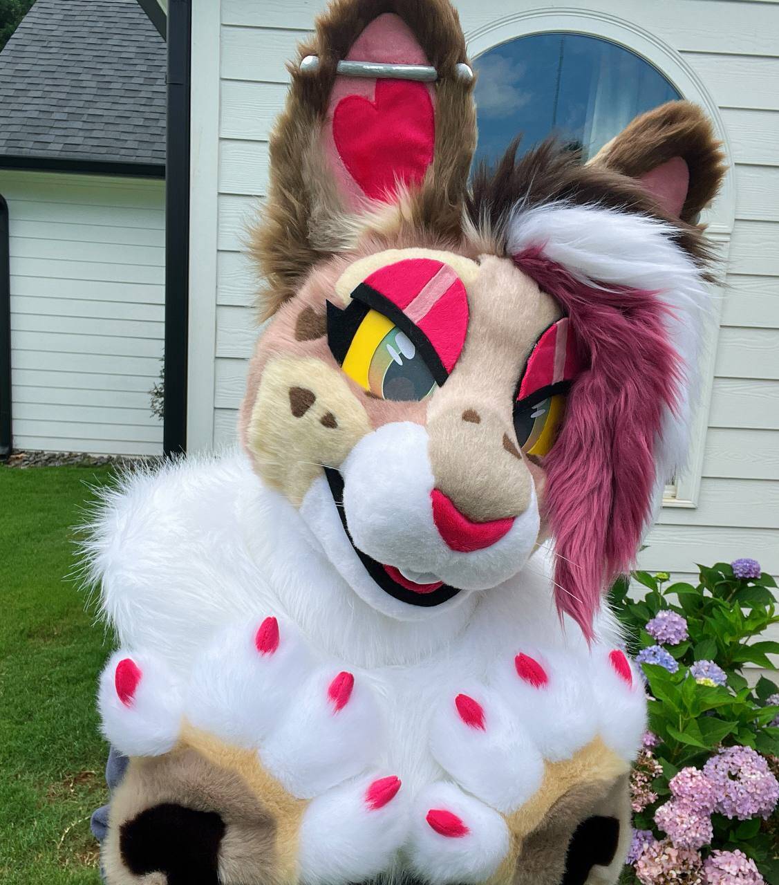 A mini partial fursuit of a feminine brown rabbit with red, pink, and white accents.