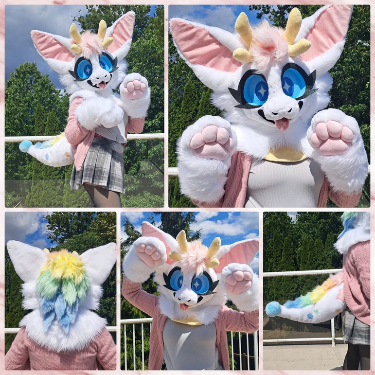 A mini partial fursuit of a white dragon with yellow deer horns and a rainbow mane.